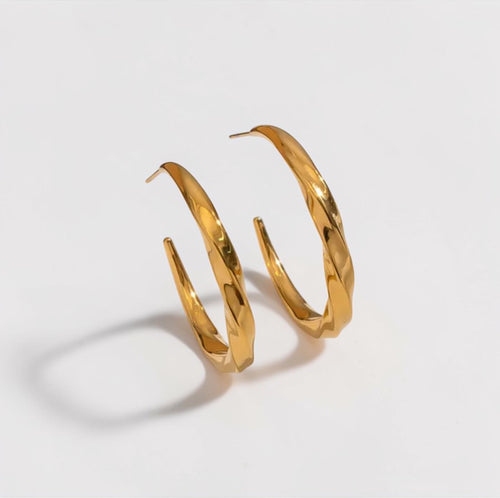 Gold hoop earrings on a light gray background