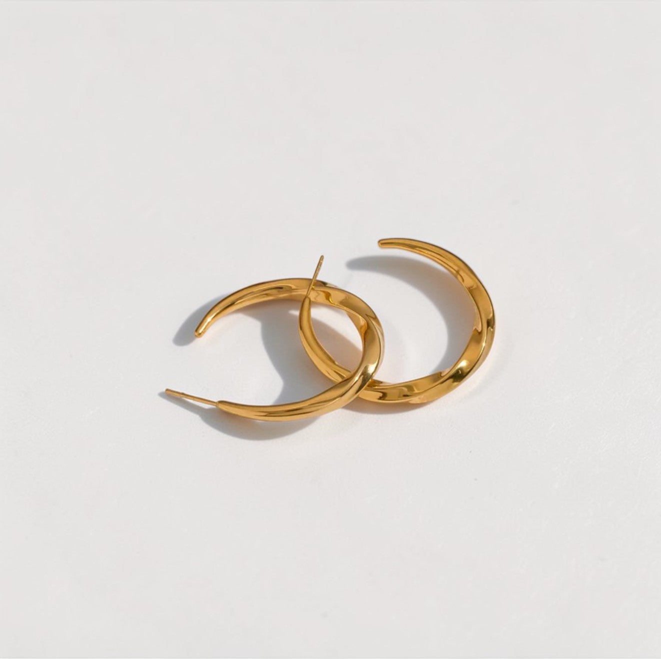 Gold hoop earrings on a light gray background