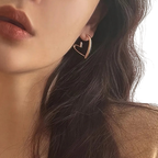 Close-up of a person wearing a gold heart-shaped earring.