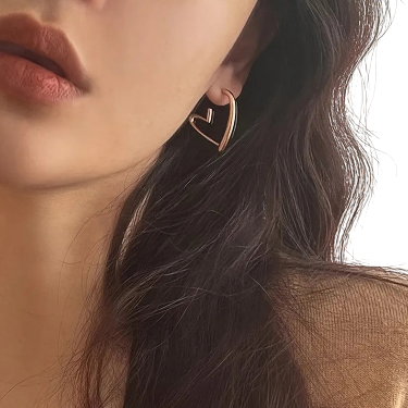 Close-up of a person wearing a gold heart-shaped earring.