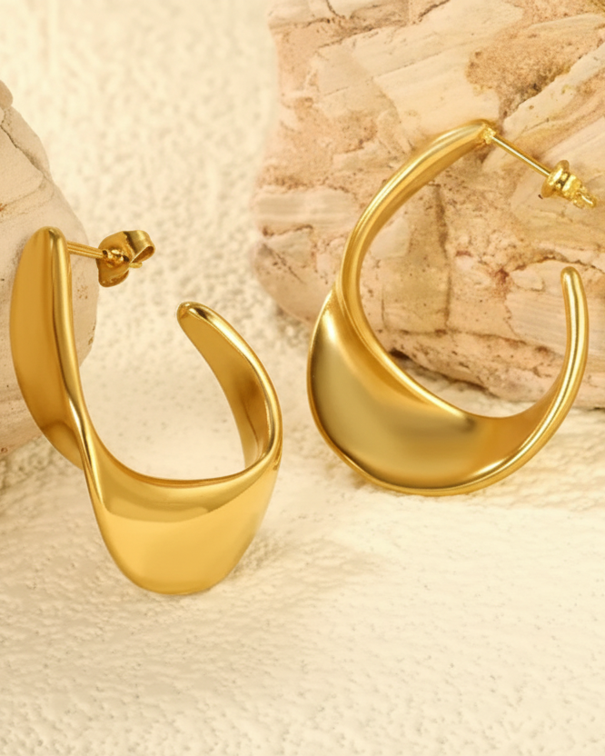 Gold hoop earrings on a textured beige surface
