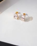 Pair of gold earrings with clear gemstones on a white surface.