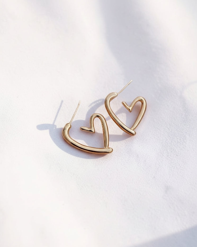 Gold heart-shaped earrings on a white background