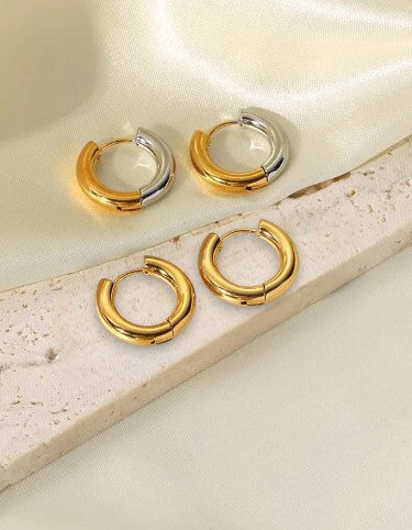 Set of gold and silver hoop earrings on a light fabric background
