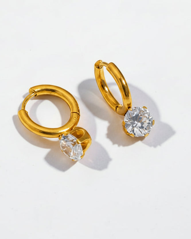 Gold hoop earrings with clear gemstones on a light gray background