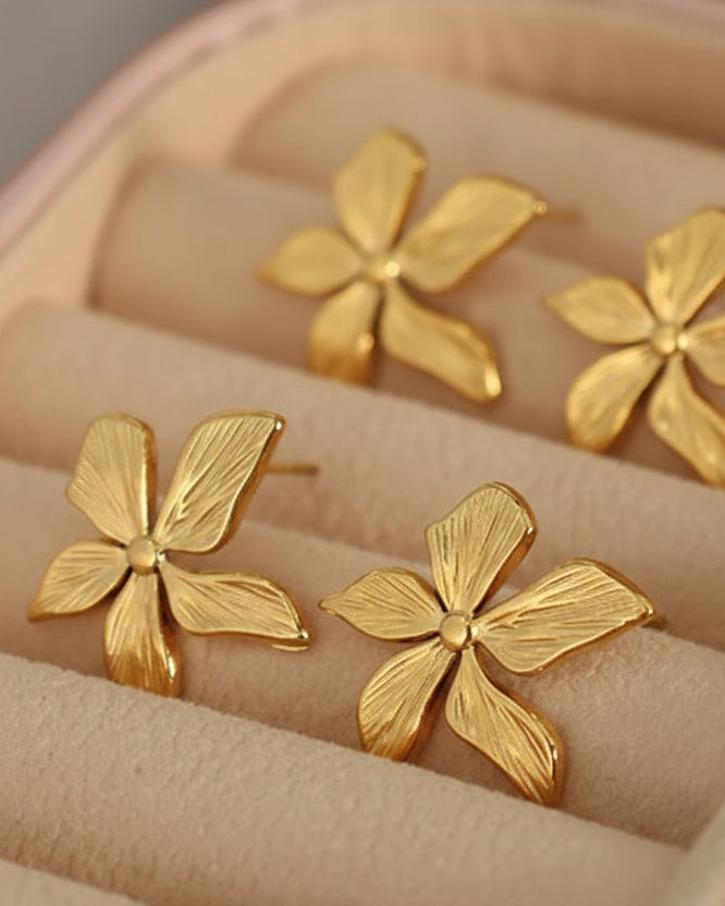 Gold flower-shaped earrings in a jewelry box