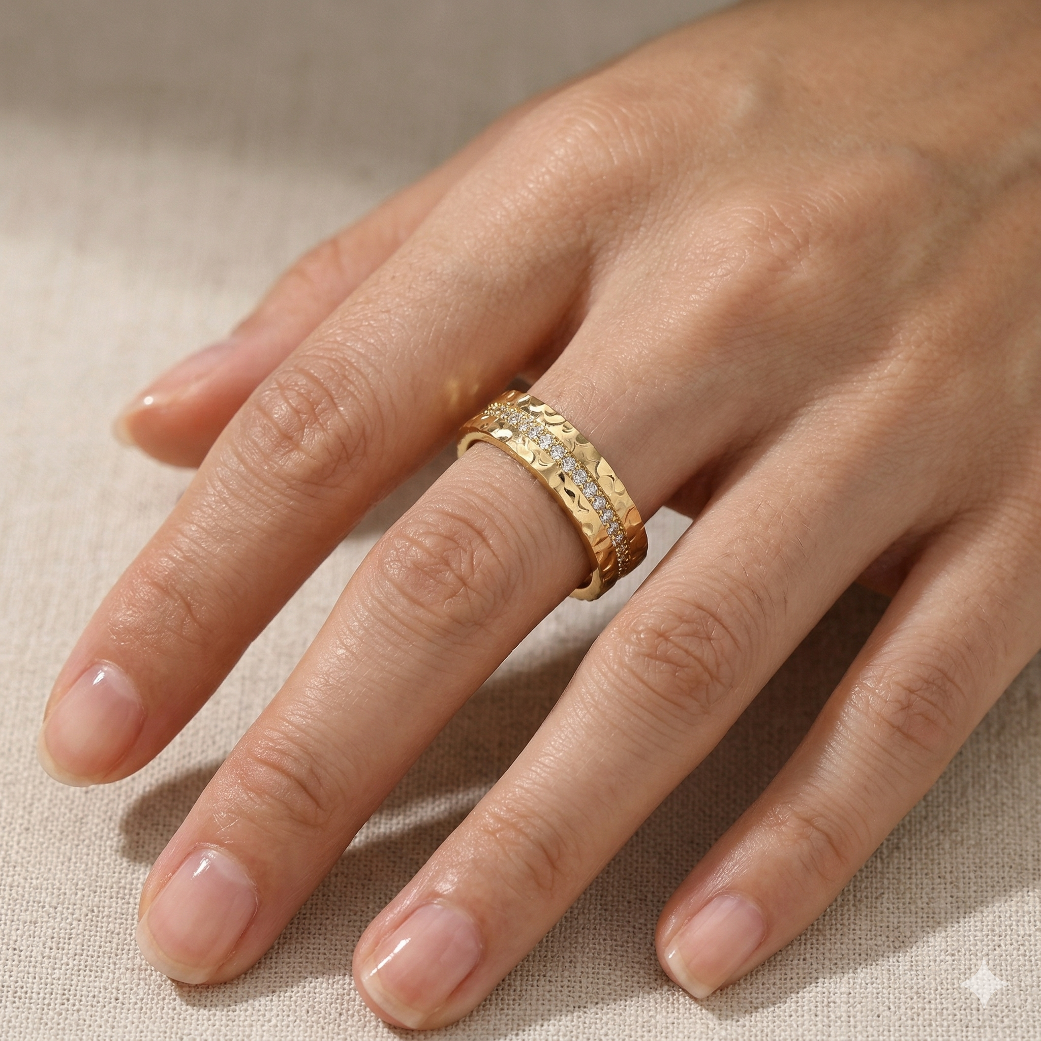 Gold ring with diamond accents on a hand against a neutral background