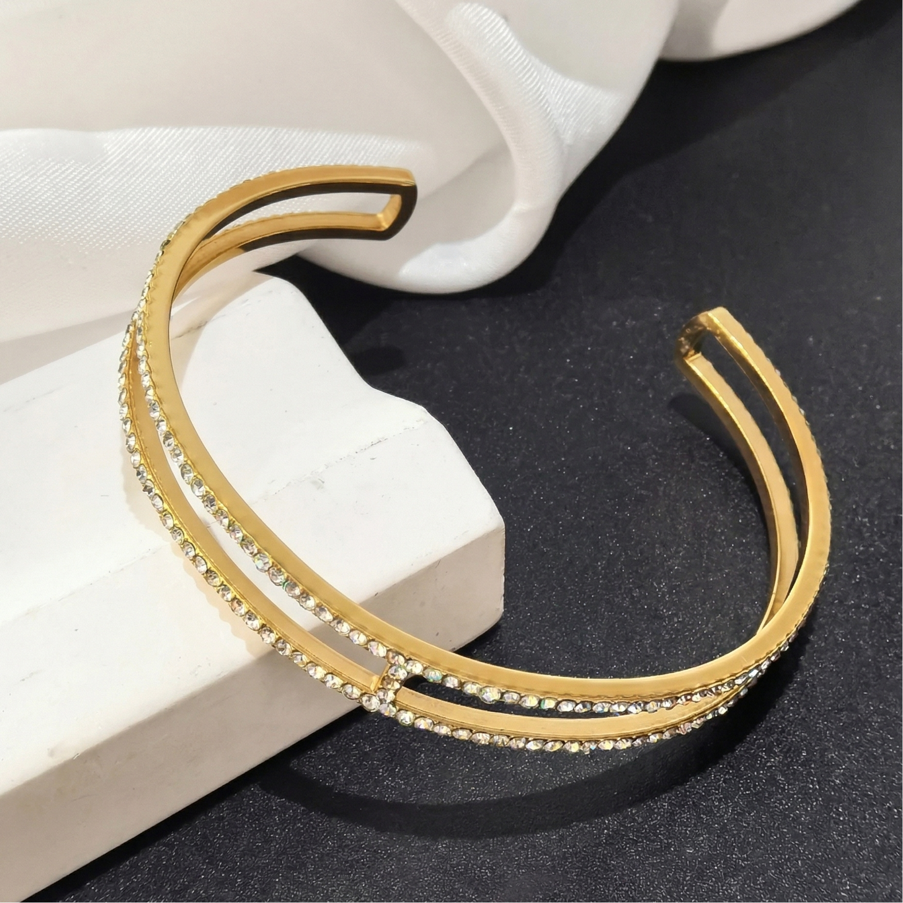 Gold bracelet with embedded stones on a black surface