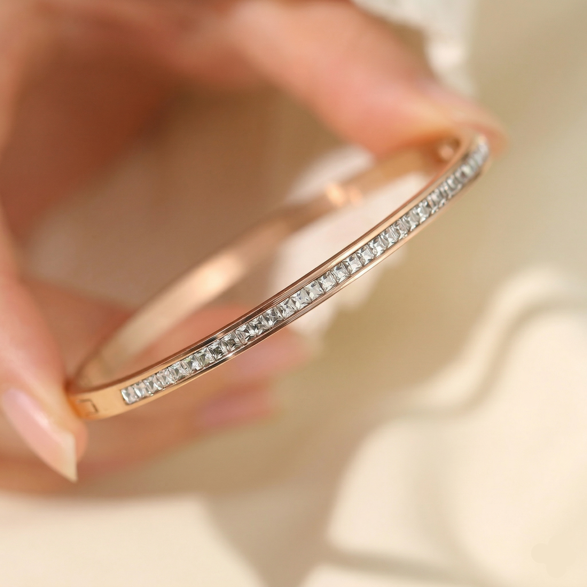Rose gold bracelet with diamonds held by a hand on a light background