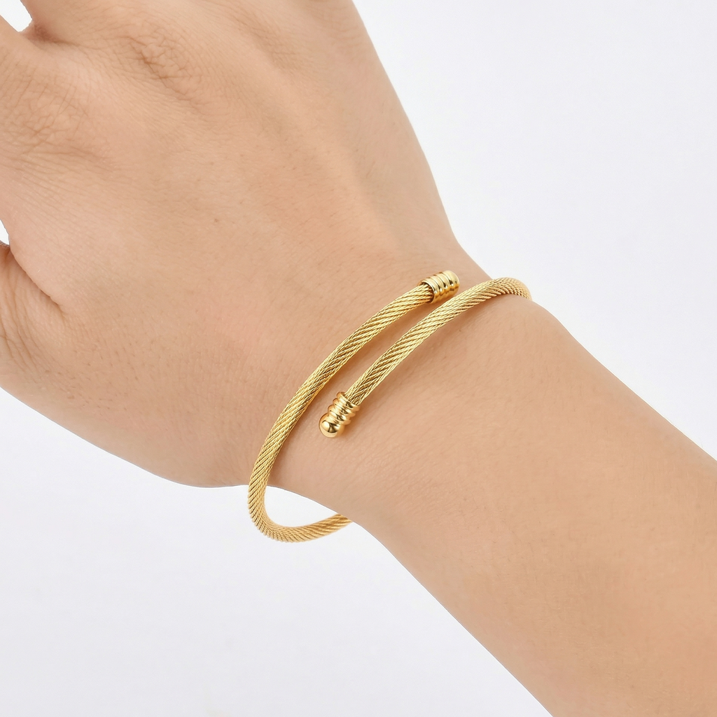 Gold bracelet on a wrist against a white background